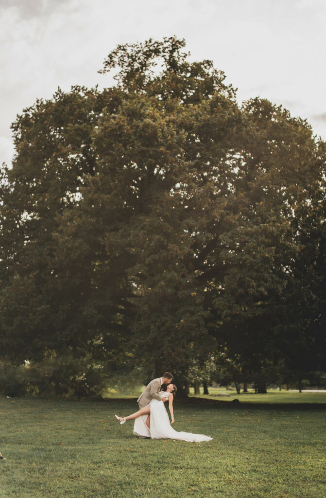 Newlyweds kiss in front of the giant oak tree.