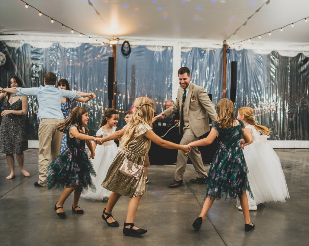 Groom dancing in a circle with flower girls and nieces.