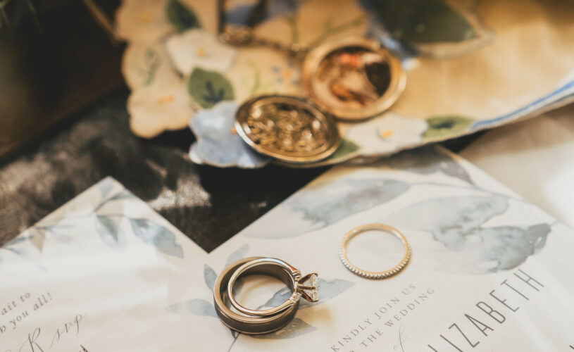 Rings and flowers laying upon the invitations.