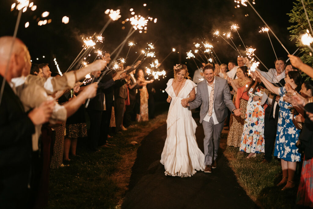 Newlyweds surrounded by guests and sparklers as they exit the reception.