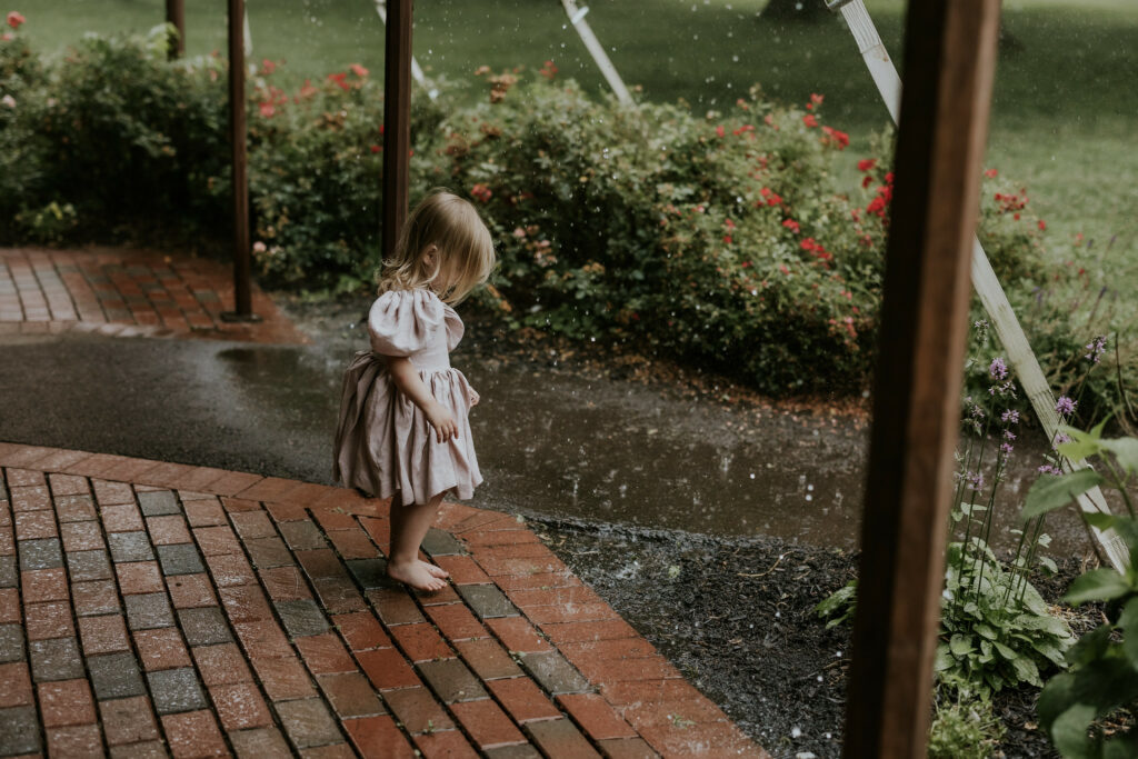 Toddler flower girl barefoot dancing in the rain.
