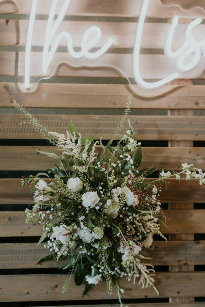 Brides bouquet under a neon sign of their name.