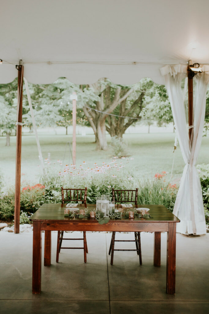 Sweetheart table with floral under the tent.