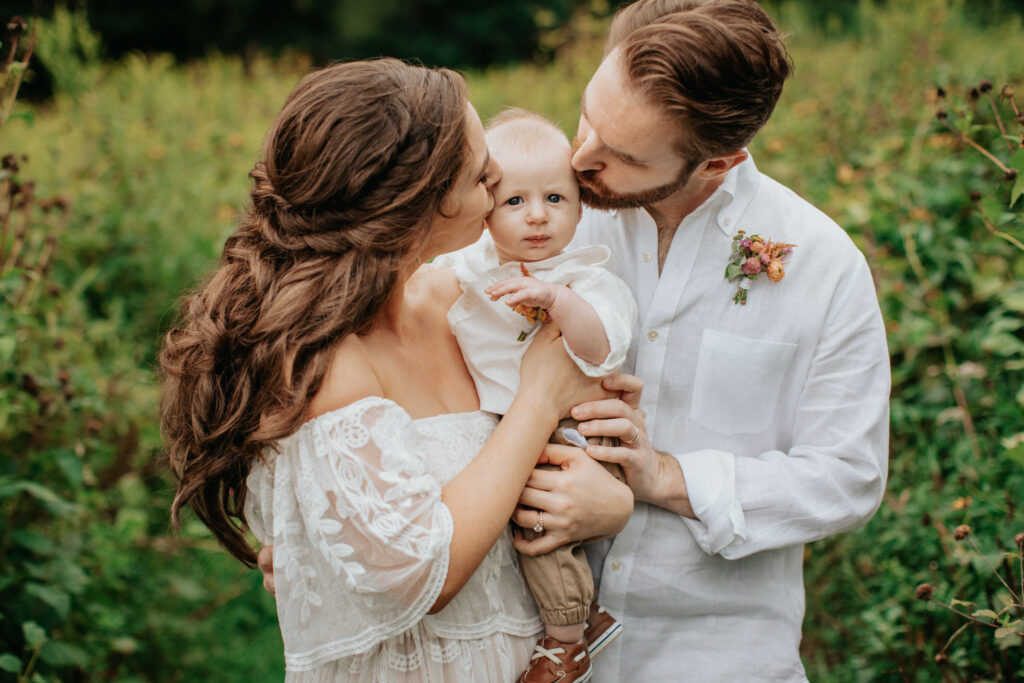 Newlyweds kiss their baby son in the garden.