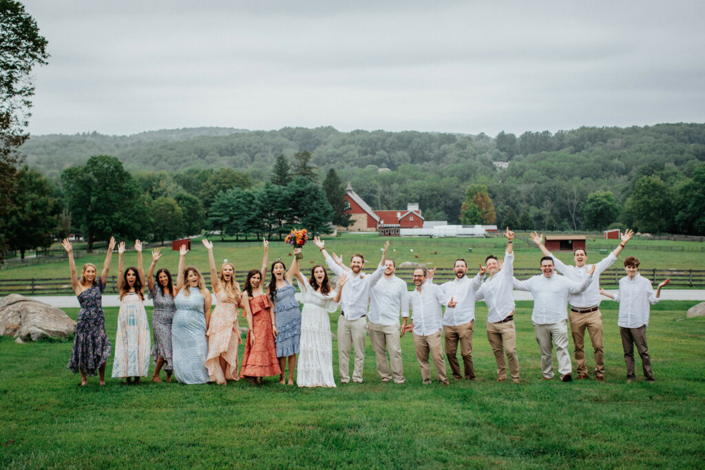 Bridal party cheers in the pasture.