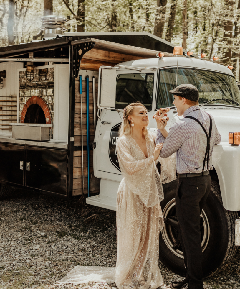 wedding couple eating pizza in front of common good pizza toof truck