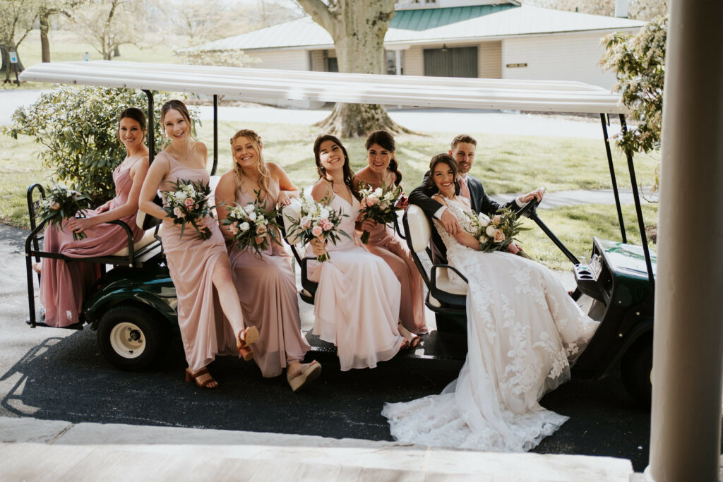 Groom driving bride and bridesmaids in golf cart.