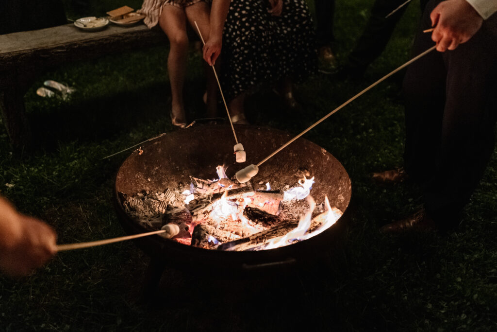 Roasting marshmallows over a lit fire pit at night at Valley View at Springton Manor Farm