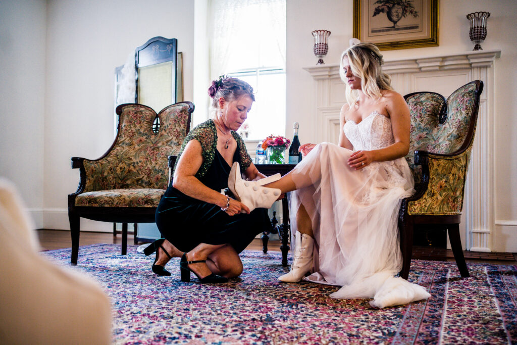 Mom helping bride put on her shoes inside of private Wedding suite at Springton Manor Farm