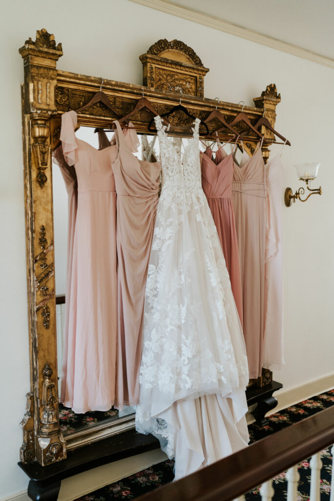 Wedding dress and bridesmaids dresses hanging on a mirror in a private wedding suite at Springton Manor Farm