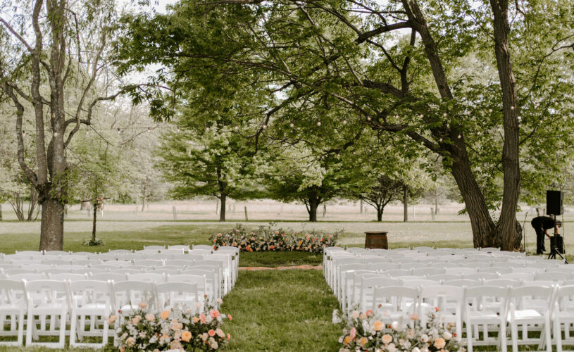 White wedding ceremony chairs in grove of trees