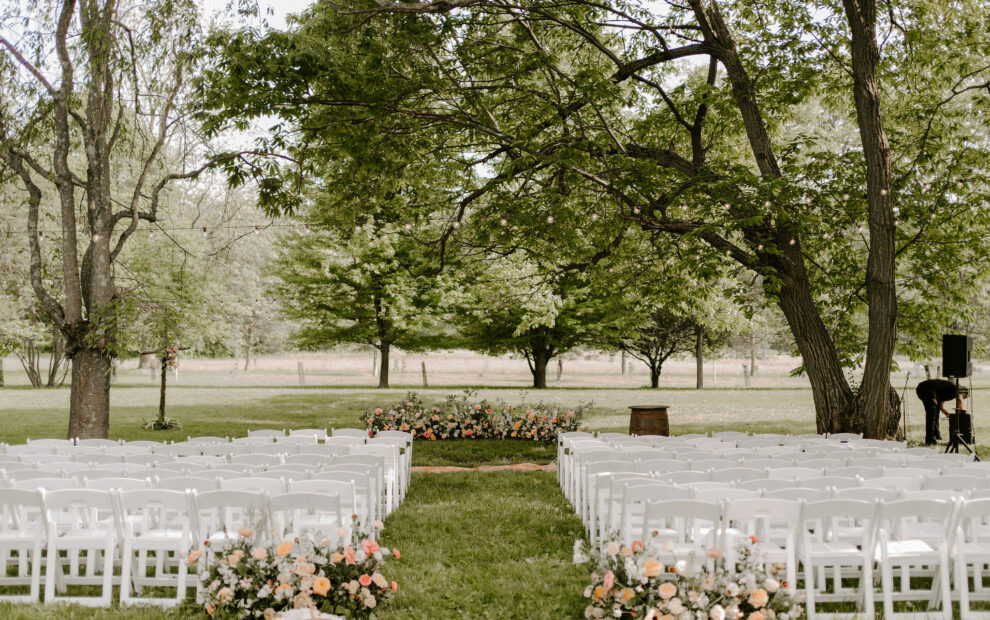 White wedding ceremony chairs in grove of trees