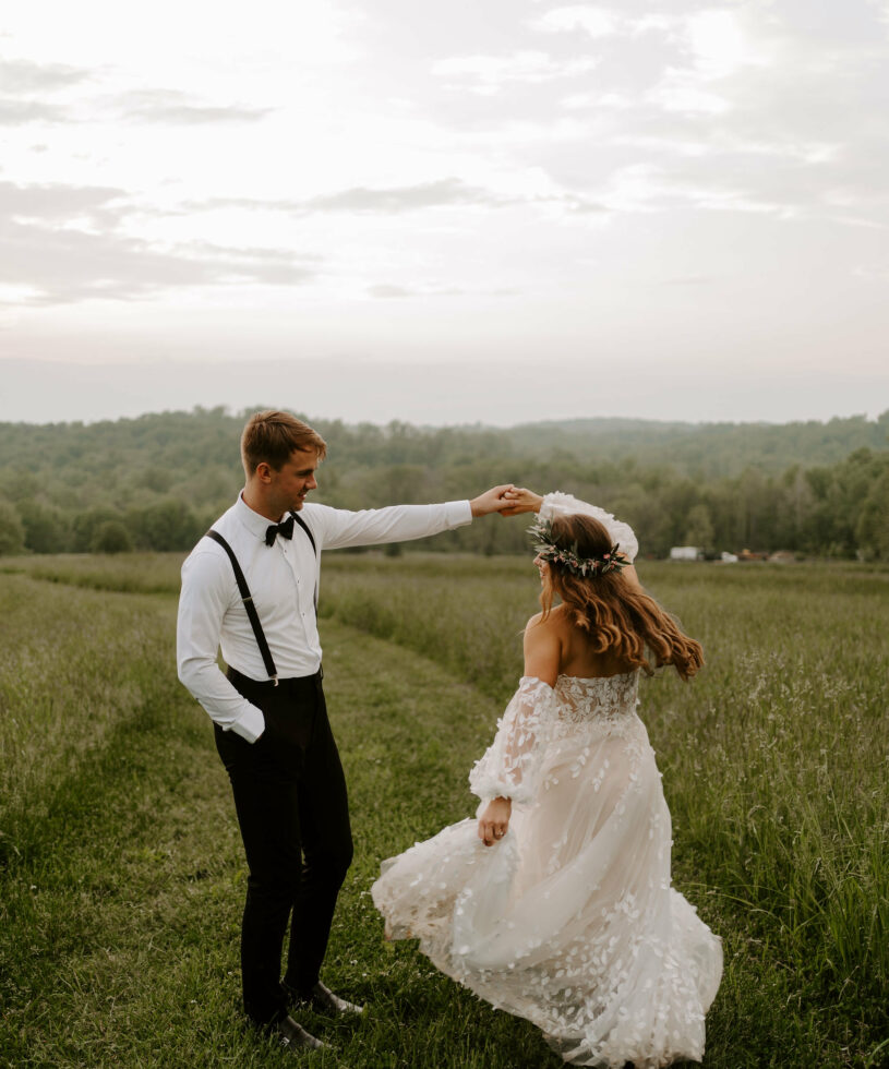 Wedding couple twirling in green field