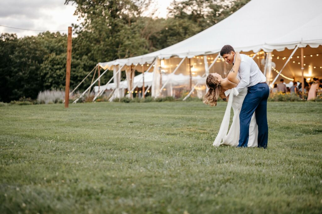 Newlyweds dance in the grass.