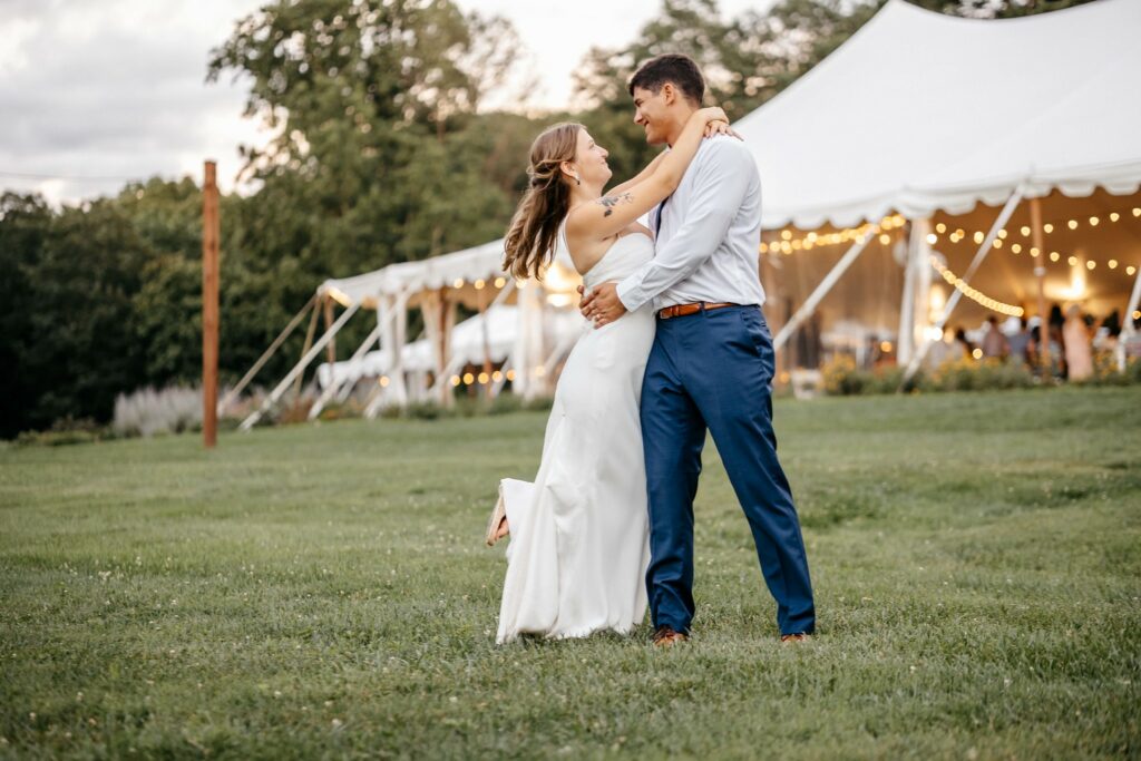 Newlyweds dance in the grass, groom spinning bride.