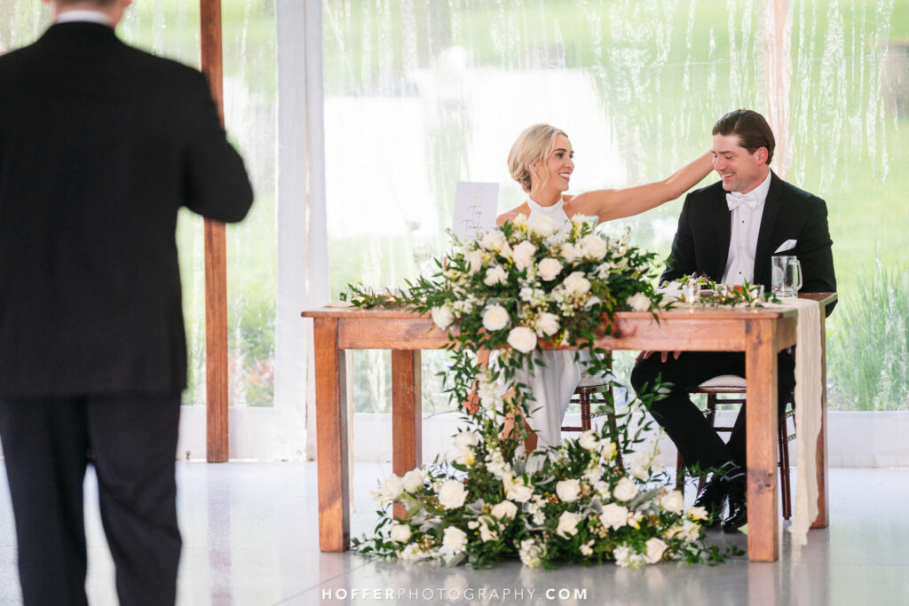 Newlyweds at the sweetheart table enjoying a speech.