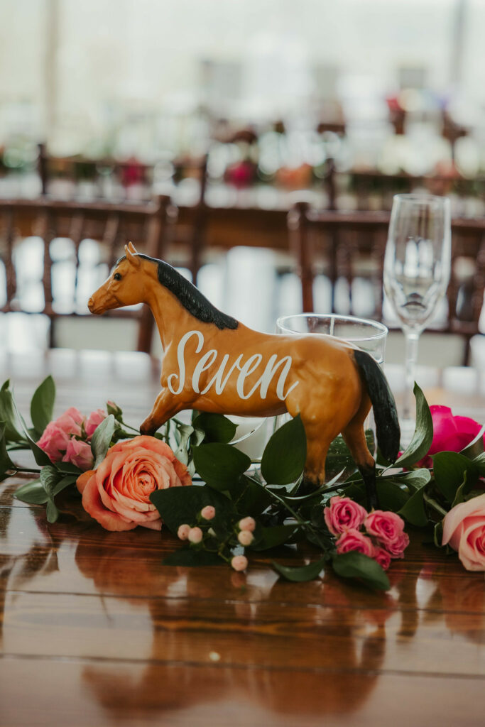 Tables with long and low floral decor with horse table numbers.