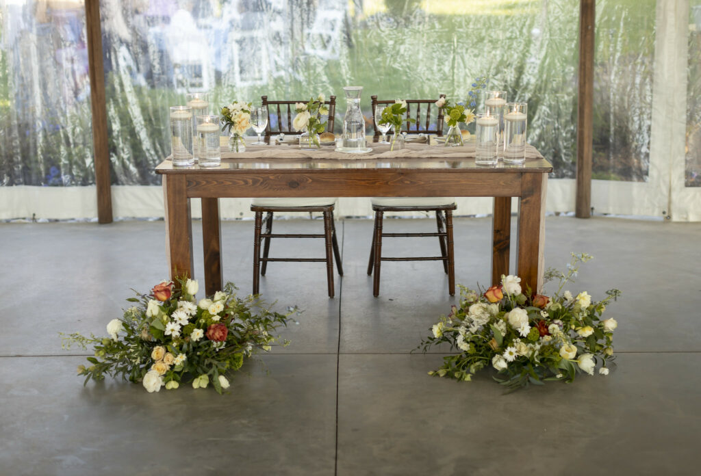 Sweetheart table with floral decor in front of both legs.