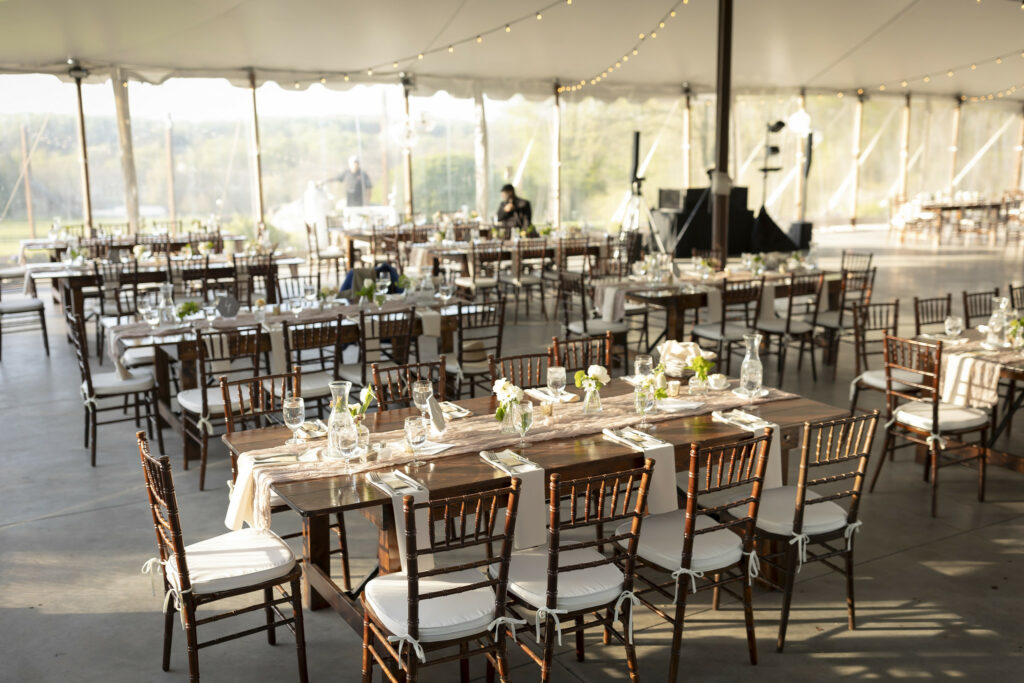 Reception tables with floral decor under tent.